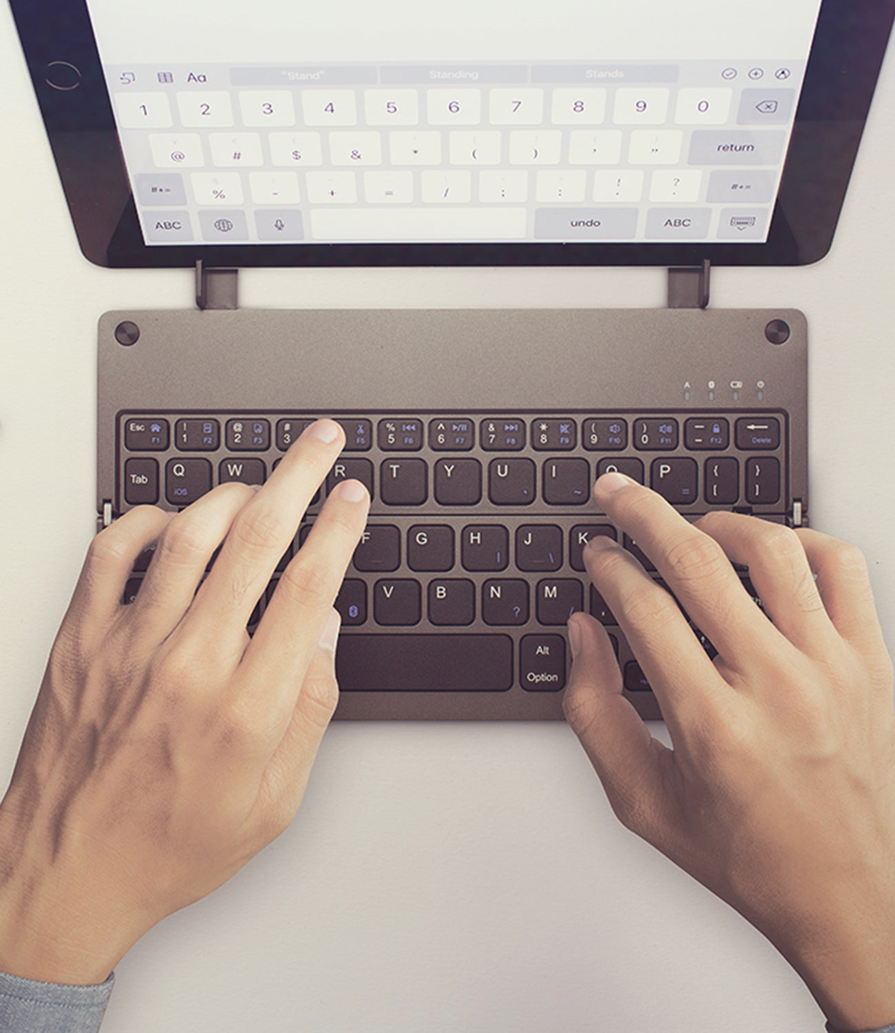 Casestudi Foldboard Stand in use, typing on an iPad, iPhone, and tablet, highlighting its versatility and functionality.
