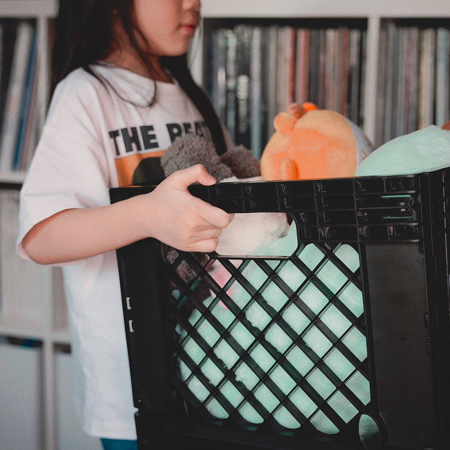 A child carrying a Thumb & Wonders black storage crate filled with toys, demonstrating a lightweight, safe, and versatile modular home organization solution.